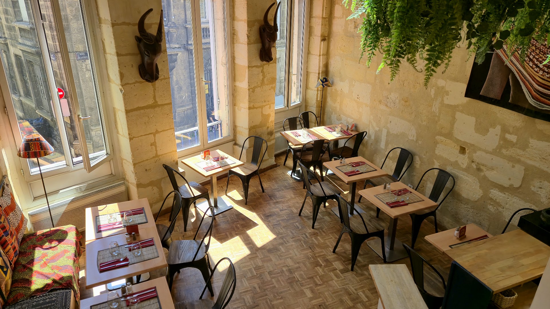 La salle lumineuse d’OKRA avec murs de pierre, plantes et tables dressées