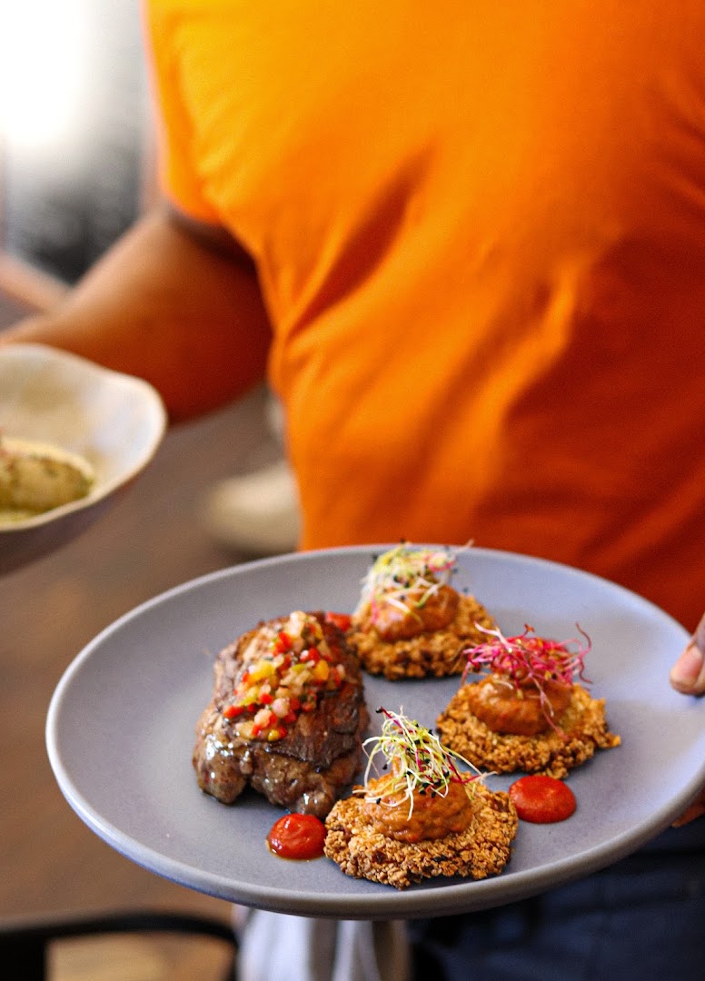 Une assiette portée avec quatre préparations garnies de condiments colorés chez OKRA